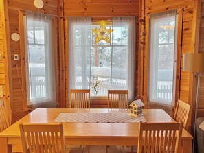 A wooden cabin with a dining table, chairs, a star-shaped light fixture, and a small house-shaped decoration.
