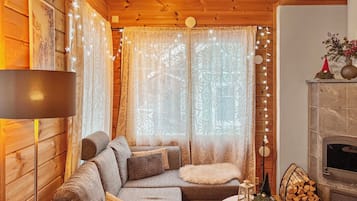 A cozy log cabin interior with a sofa, a small table, and a fireplace.