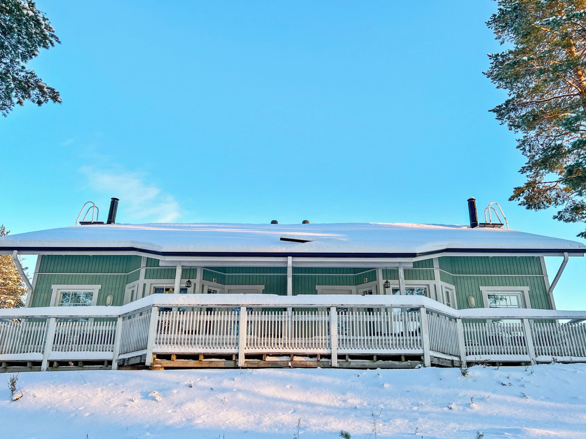 Ein zweistöckiges Haus mit schneebedecktem Dach und einem Balkon.