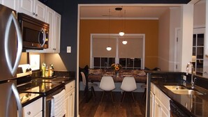 A modern kitchen with a dining area, featuring a large refrigerator, microwave, and double sink. - Community has three pools & tennis courts (Rehoboth Beach)