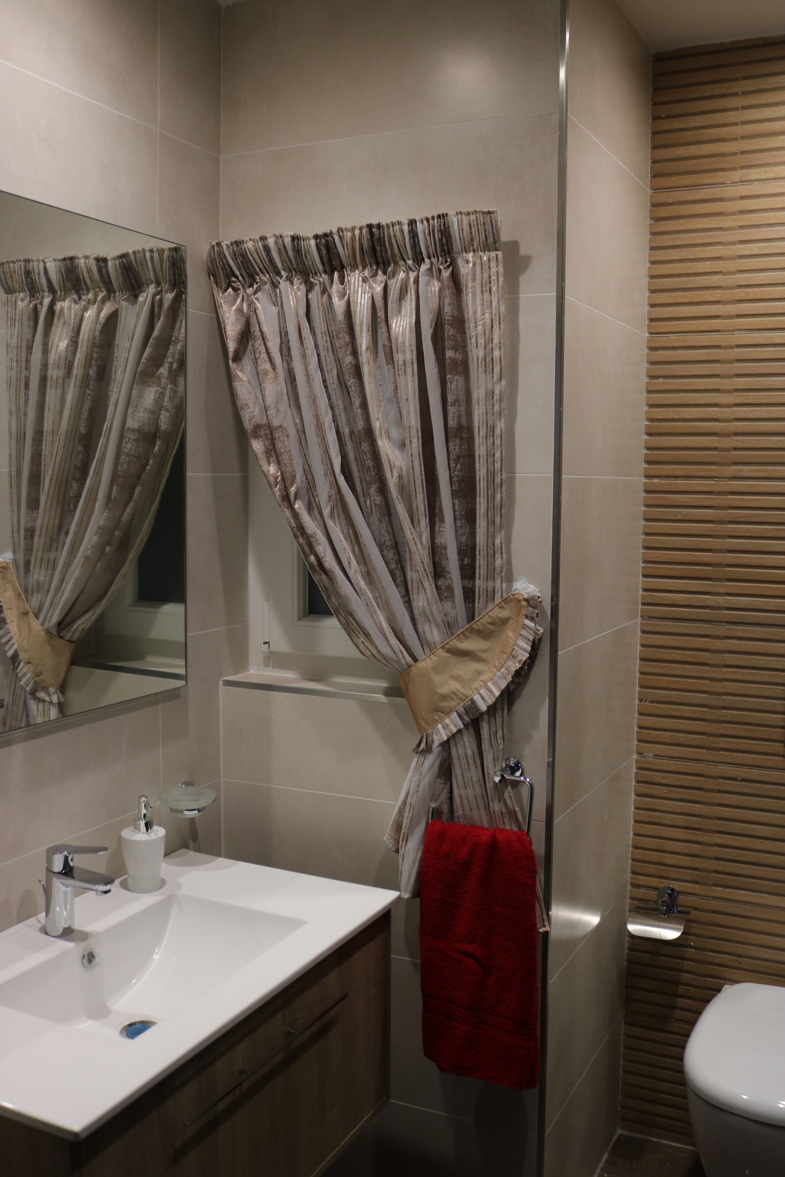 A bathroom with a white sink, mirror, and shower curtain.