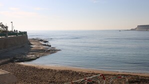 A coastal view with a sandy beach, a rocky outcrop, and a clear sky. - Seaside Apartment (Marsaskala)