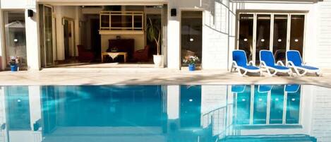 Alberca al aire libre, sombrillas en la alberca y camastros