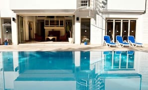 Una piscina al aire libre, sombrillas, sillones reclinables de piscina