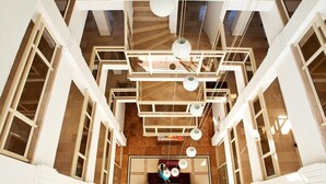 A high-ceiling atrium with a central seating area, multiple staircases, and hanging pendant lights. - Villa Gizem (Manavgat)