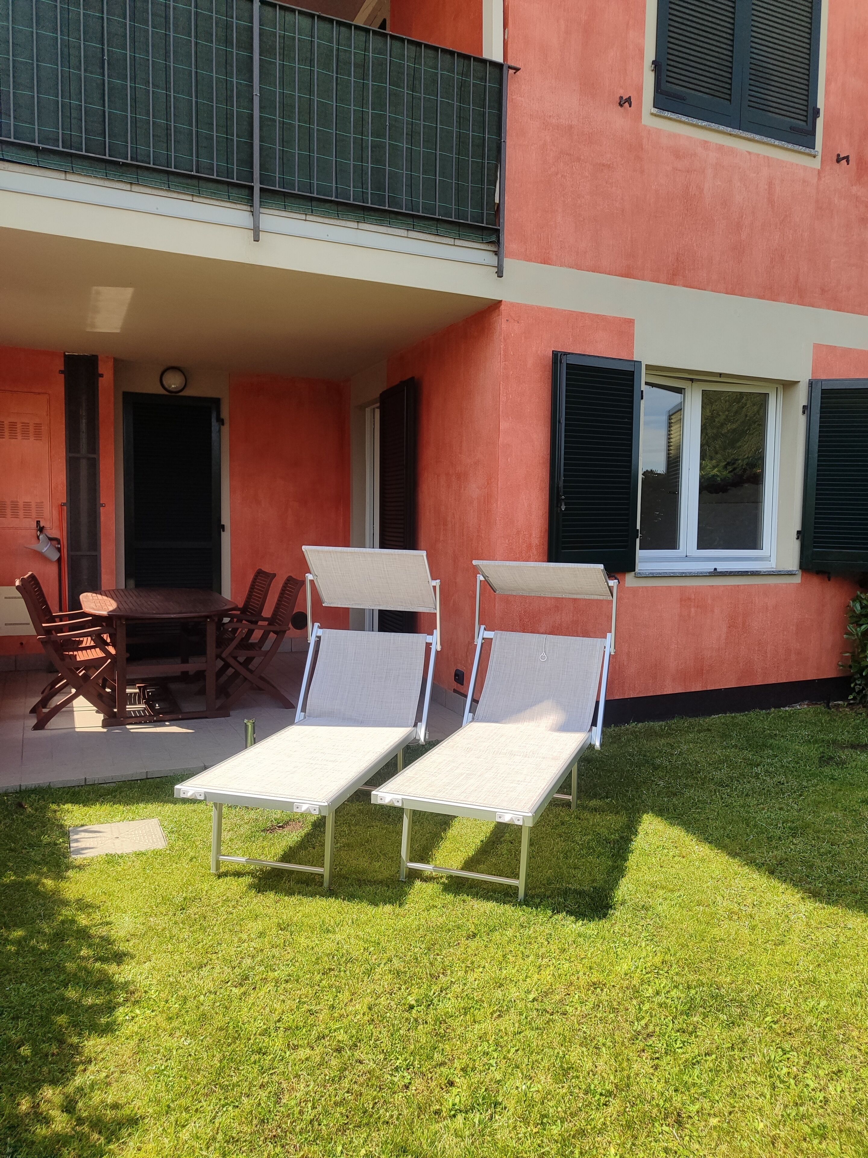 A two-story building with a balcony, outdoor seating, and a well-maintained lawn.
