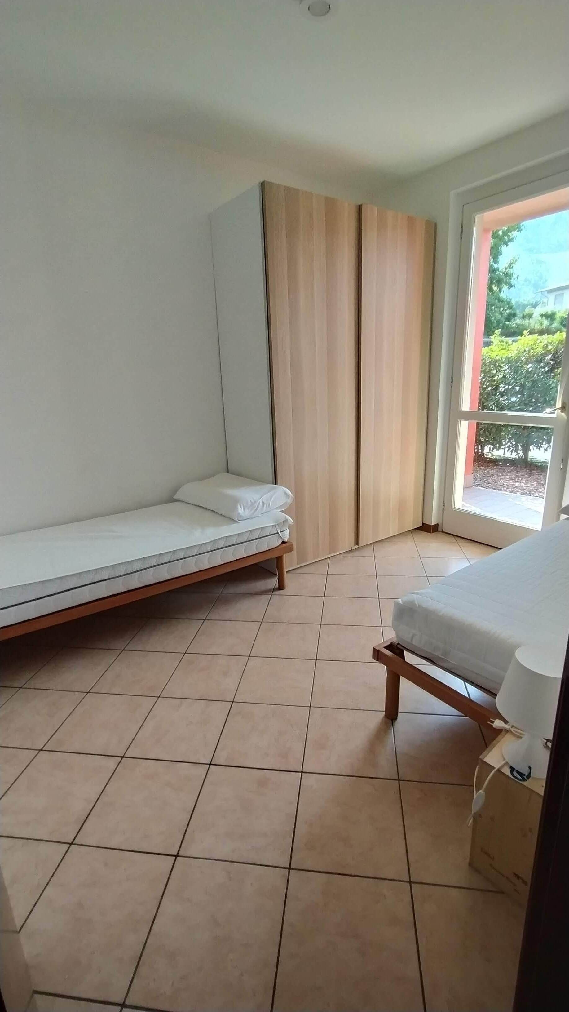 A room with a bed, a chair, a window, and a door.