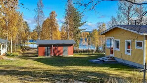 A cabin with a red exterior and a yellow exterior, surrounded by a grassy area and trees. - Huitsin nevada by Interhome (Muonio)