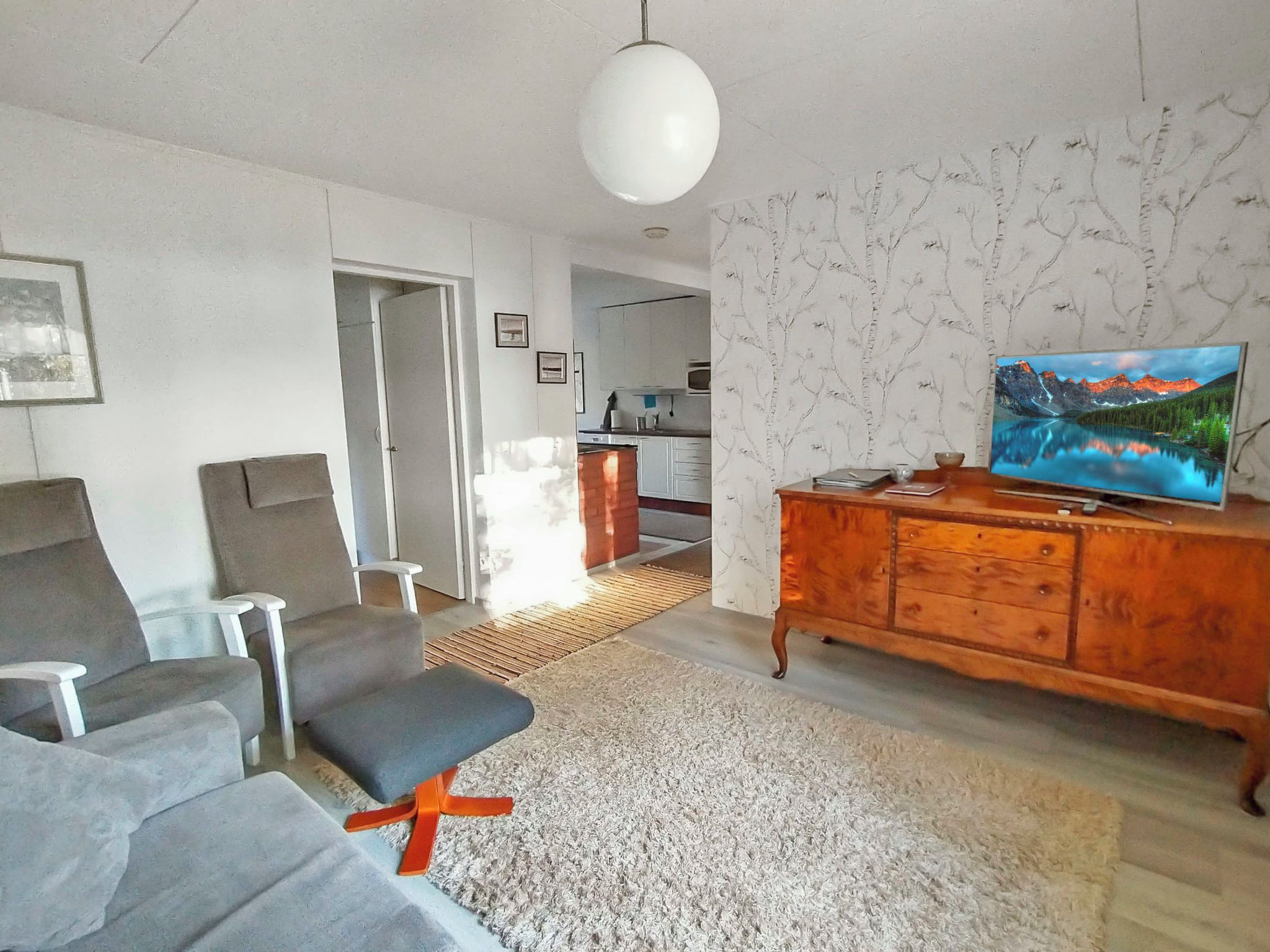 Een woonkamer met een bank, een televisie en een houten kast.