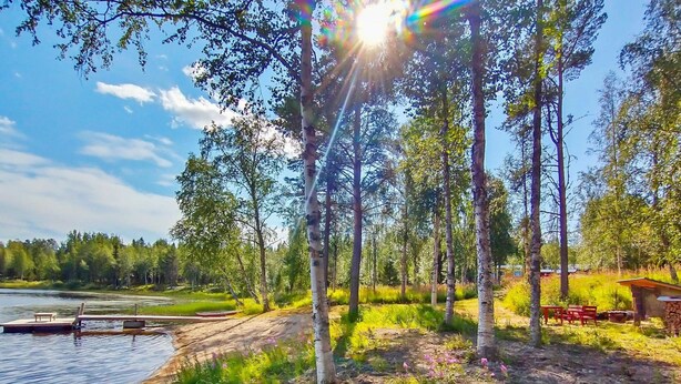 A lakeside cabin with a dock, surrounded by trees and a grassy area. - Huitsin nevada by Interhome (Muonio)