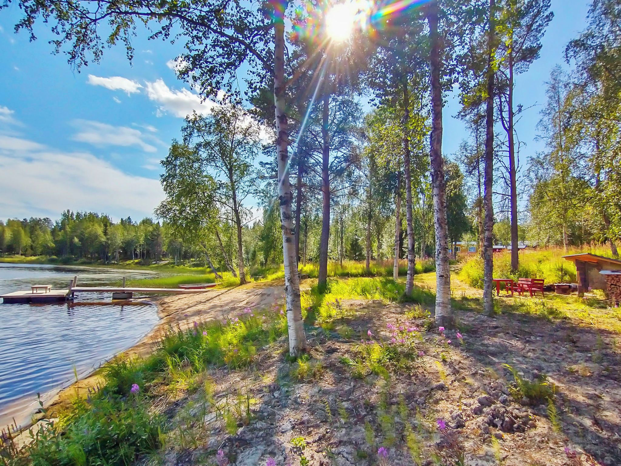 Un chalet au bord du lac, doté d’un quai, entouré d’arbres et offrant une vue sur un ciel dégagé.
