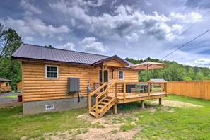 A wooden cabin with a metal roof, a wooden deck, and a covered outdoor seating area. - Private Hot Tub: Tuckasegee River Couple's Escape (Bryson City)