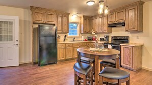 Una cocina con armarios de madera, un refrigerador, una estufa y un comedor con taburetes.