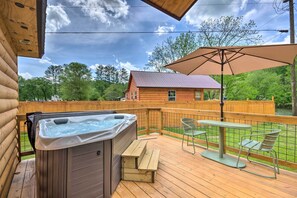 A wooden deck with a hot tub, picnic table, and umbrella. - Private Hot Tub: Tuckasegee River Couple's Escape (Bryson City)