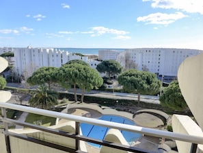 Área residencial com piscina, árvores e edifícios brancos ao fundo.