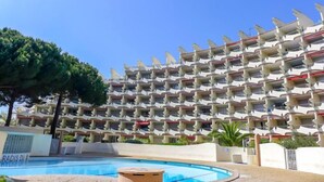 Ein mehrgeschossiges Hotel mit einer markanten, wellenförmigen Fassade, einem Swimmingpool und blauem Himmel.