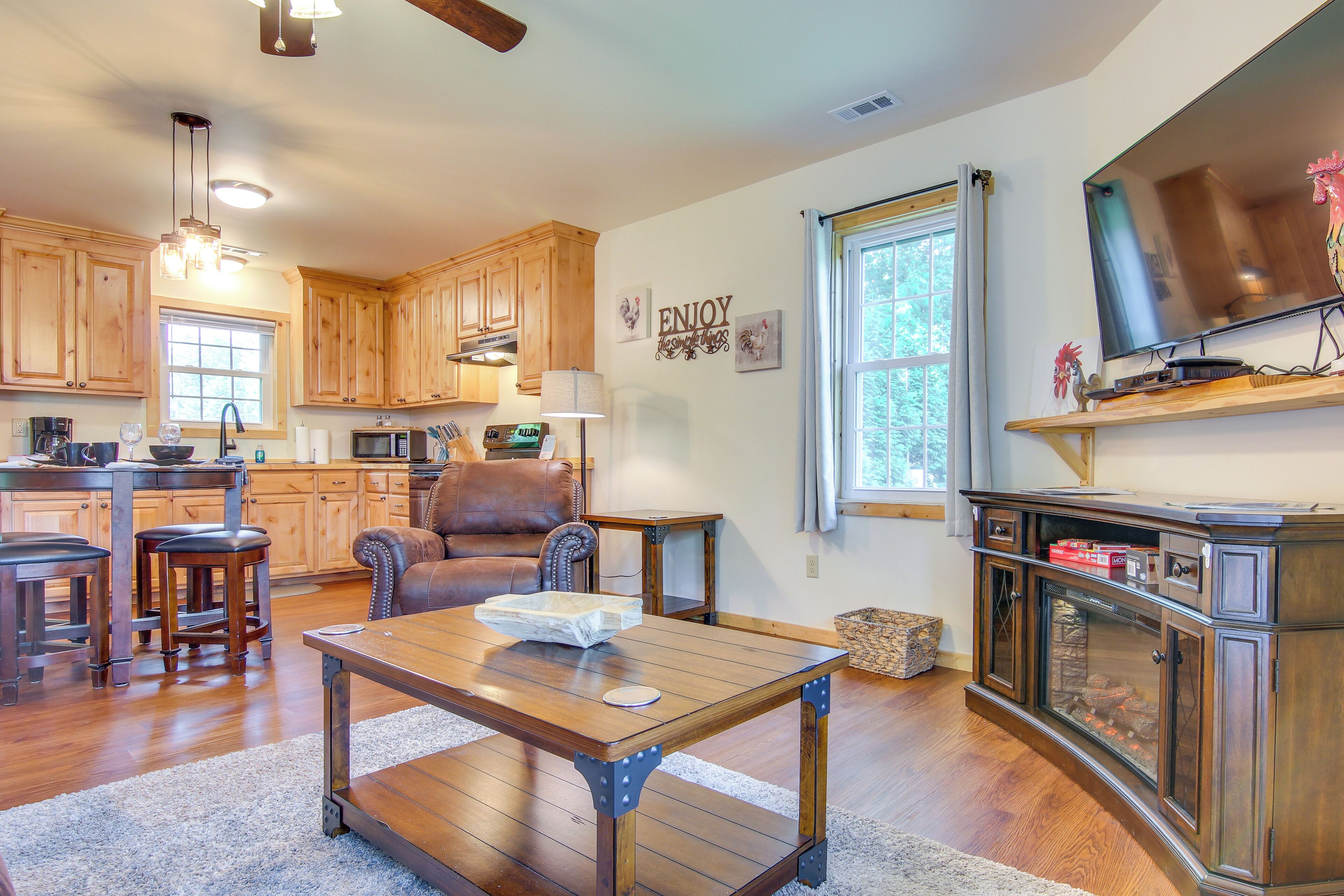 A spacious kitchen with wooden cabinets, a dining area with a table and chairs, and a large television on a wooden stand.