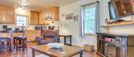 A spacious kitchen with wooden cabinets, a dining area with a table and chairs, and a large television on a wooden stand.