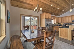 Une cuisine spacieuse dotée de meubles en bois, d’un grand îlot central et d’un coin repas avec une table et des chaises en bois.