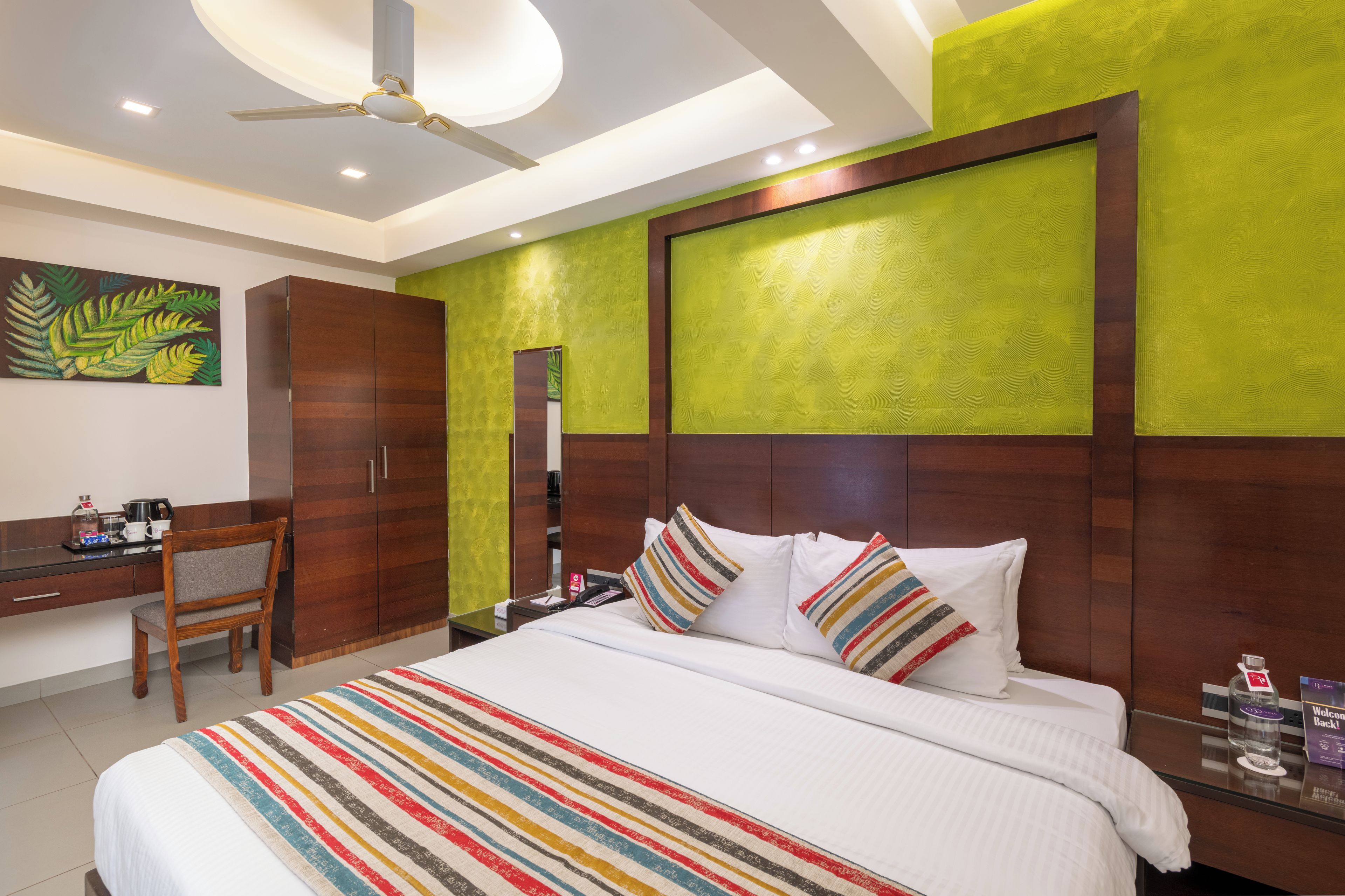 A hotel room with a bed, a desk, a chair, and a large mirror.