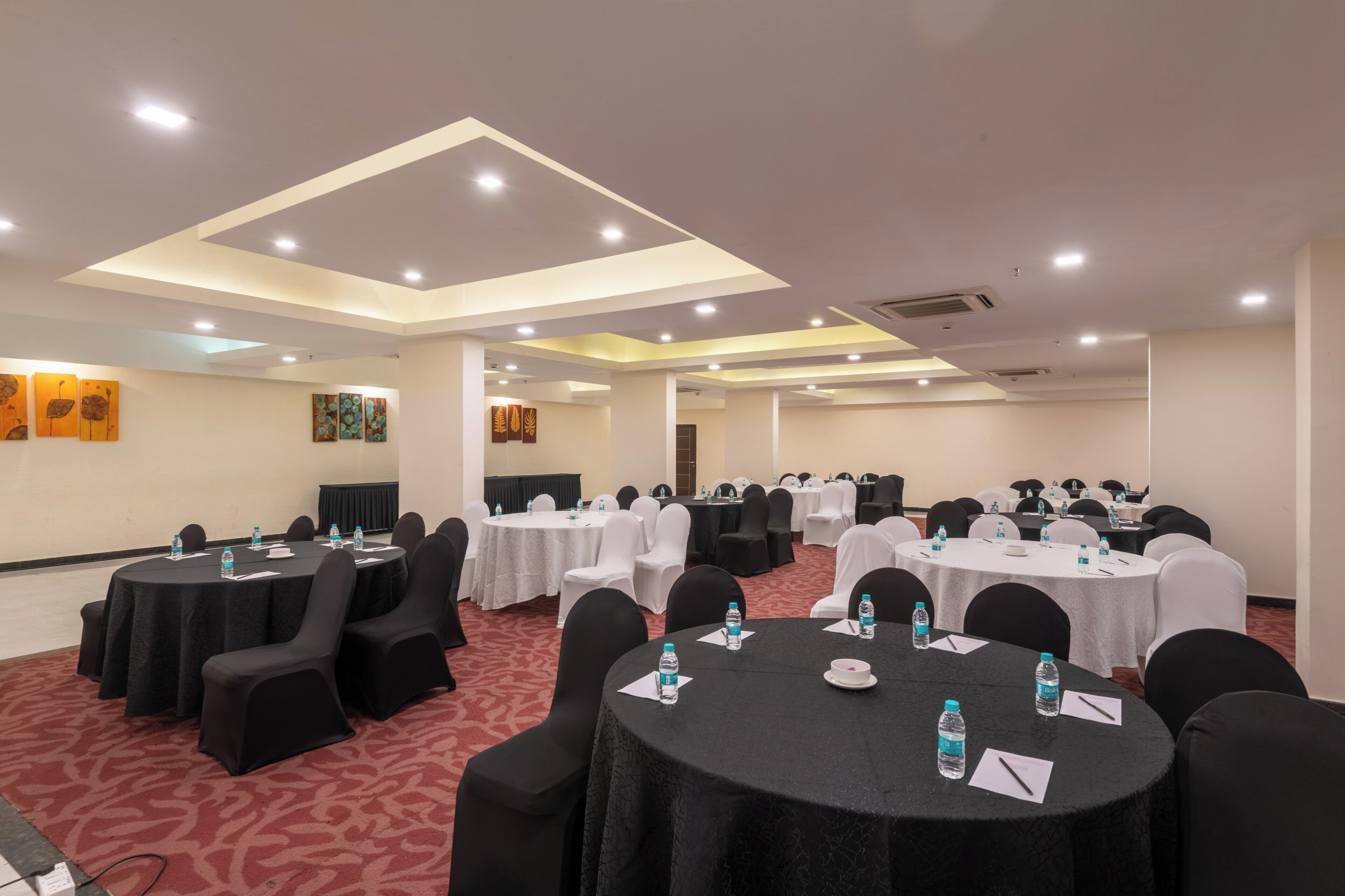 A conference room with multiple tables and chairs, equipped with water bottles and nameplates.