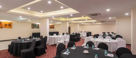 A conference room with multiple tables and chairs, equipped with water bottles and nameplates.
