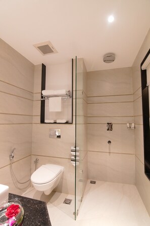 Un baño moderno con ducha envuelta en vidrio, inodoro y lavamanos con encimera de mármol.