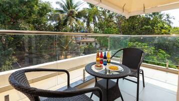 A balcony with wicker furniture, a glass table, and bottles of beverages.