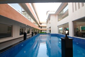 A swimming pool with a tiled blue floor, surrounded by white walls and a glass ceiling. - Regenta Central North Goa (Arpora)