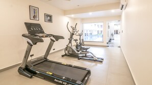 A gym with treadmills, stationary bikes, and a ceiling fan. - Regenta Central North Goa (Arpora)