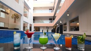 Eine Poolbar mit verschiedenen Cocktails und einem Pool im Hintergrund.