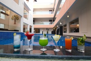 Un bar junto a la piscina, con diferentes cócteles y una piscina al fondo.