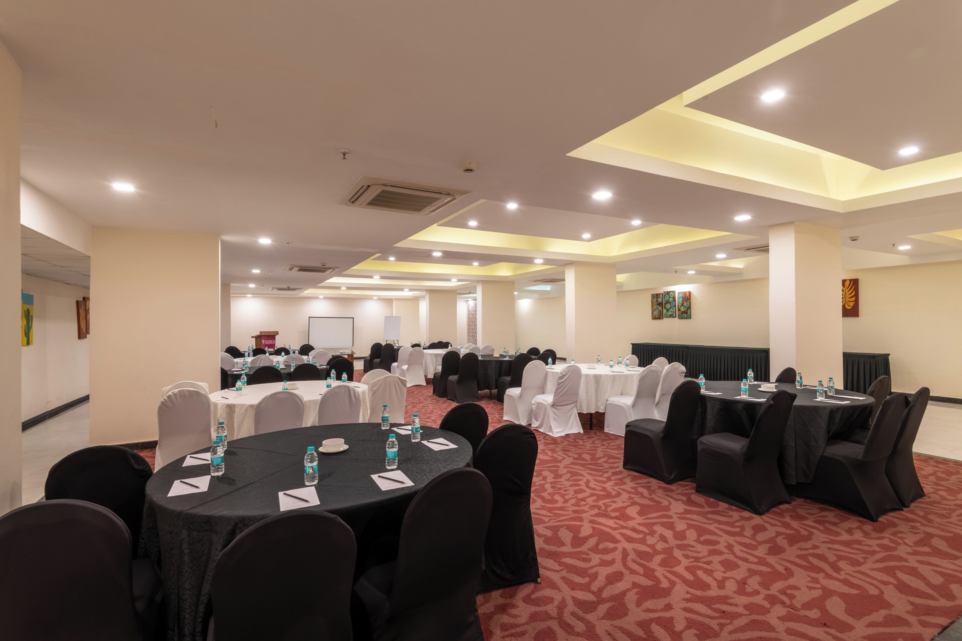 A conference room with round tables, chairs, and water bottles.
