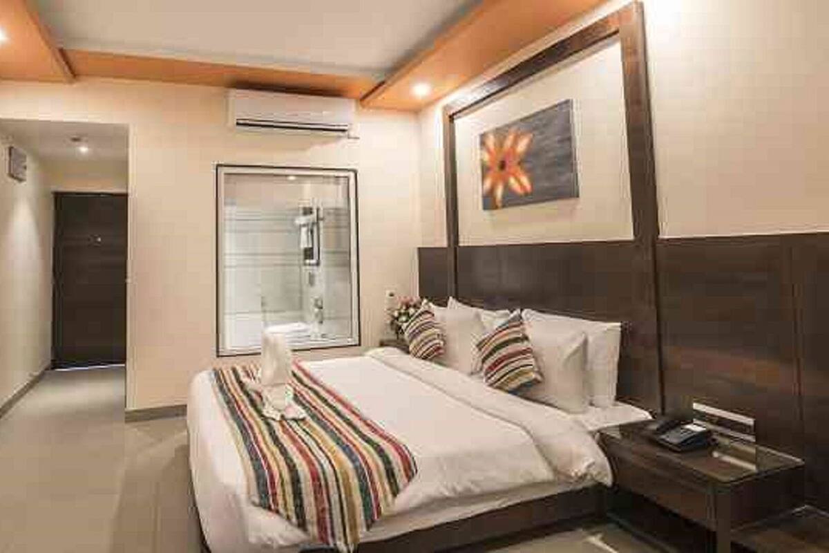 A hotel room with a bed, bedside table, and a TV on the wall.
