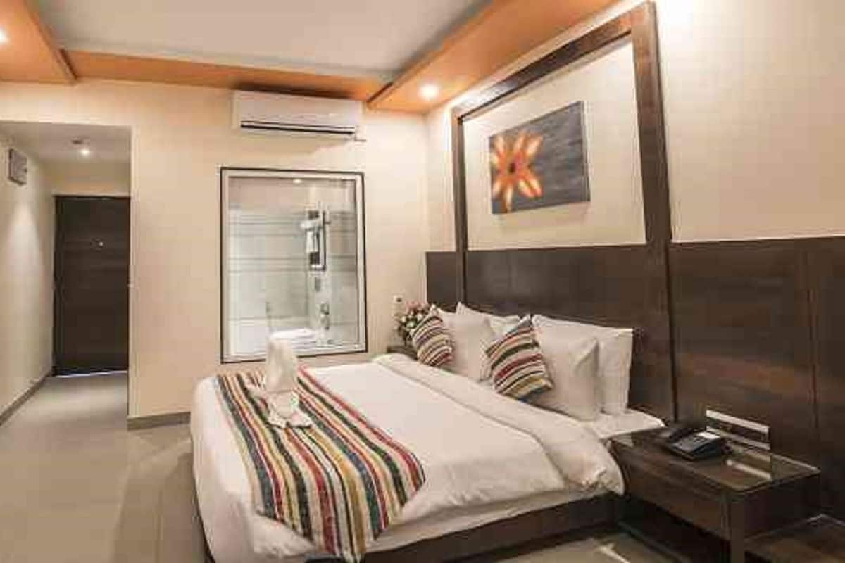 Ein Hotelzimmer mit Bett, Nachttisch und Fernseher an der Wand.