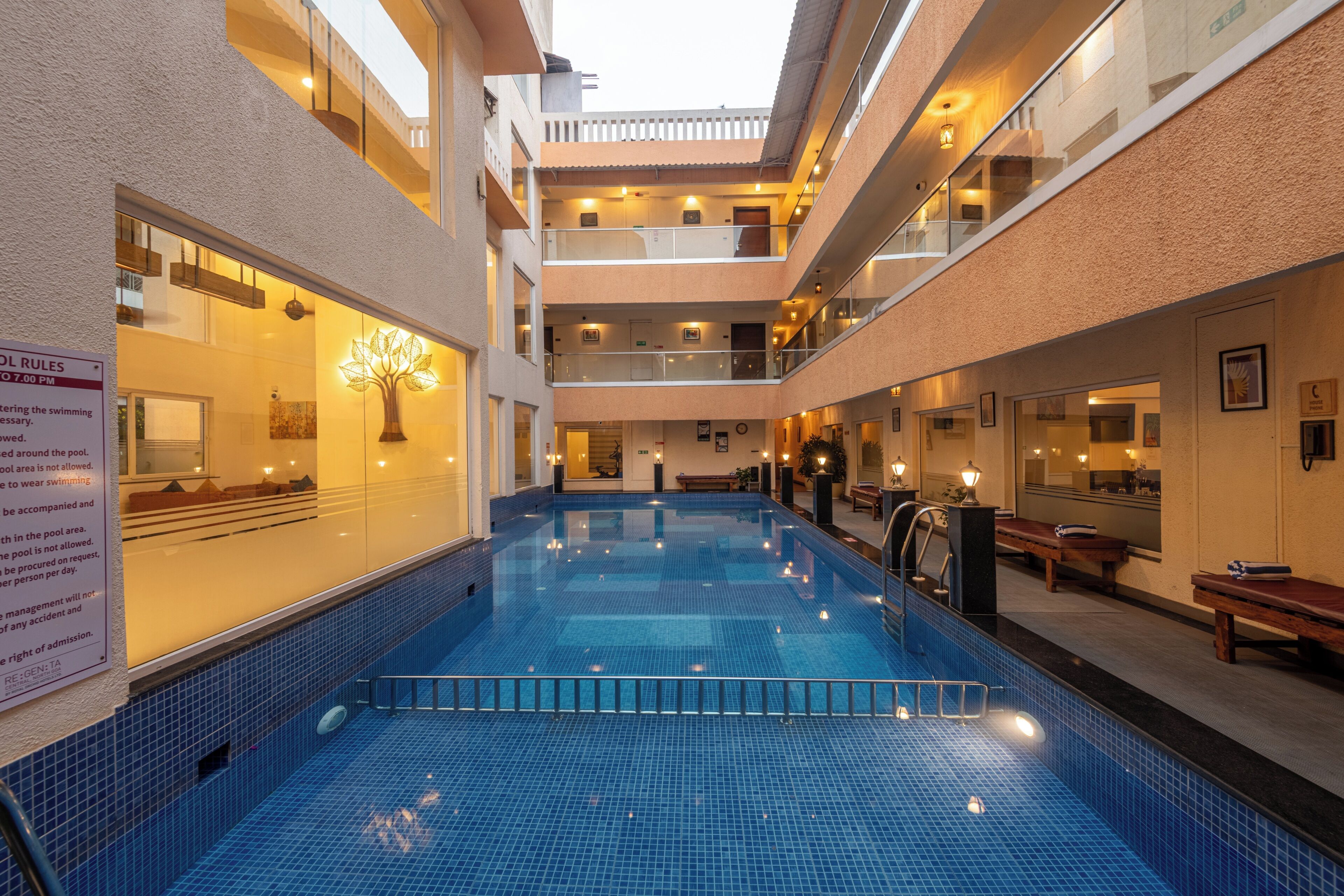 A multi-level indoor swimming pool with a tiled floor and a glass barrier.