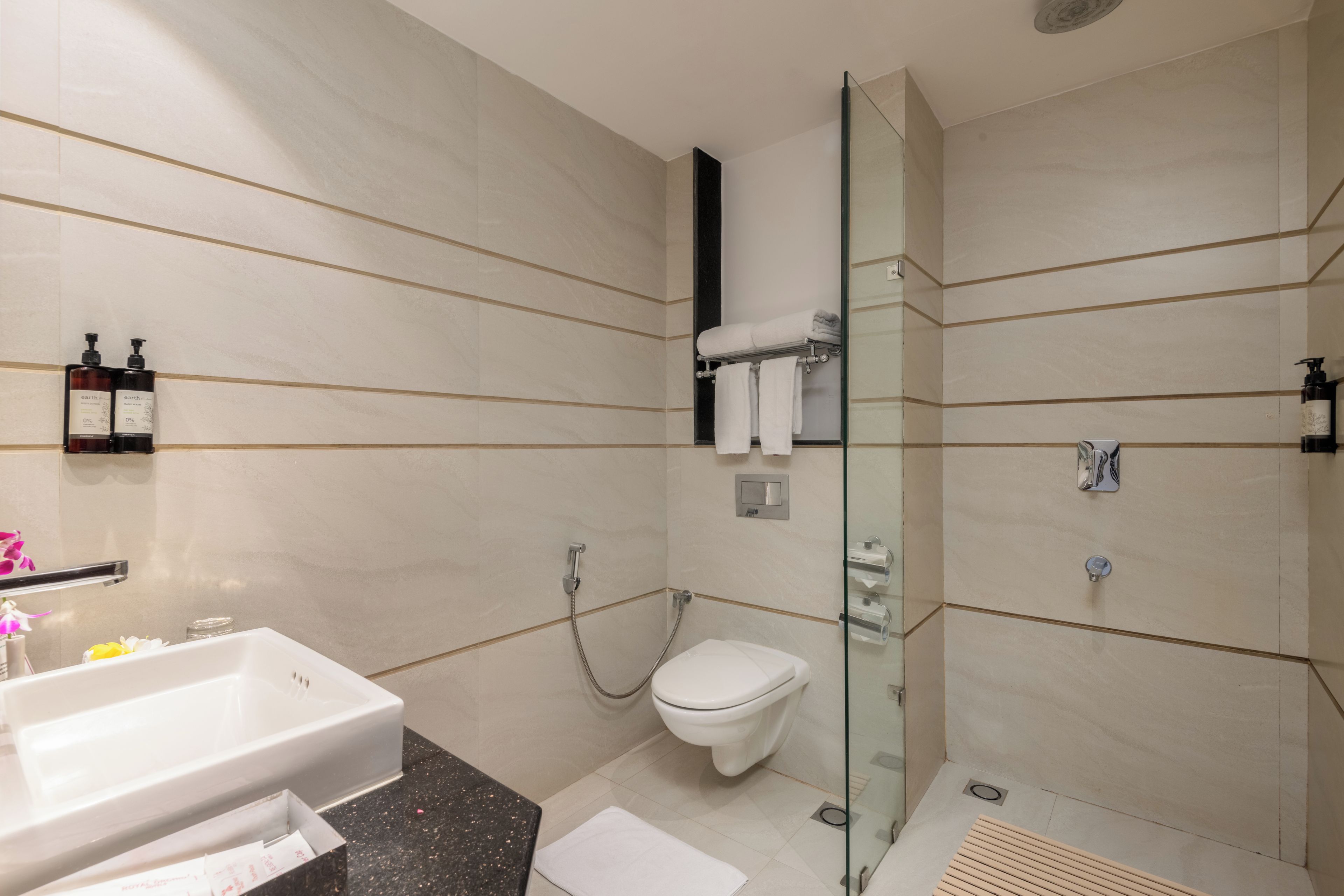 A modern bathroom with a glass-enclosed shower, a white toilet, and a sink with a marble countertop.