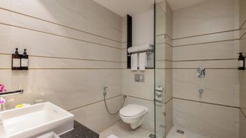 A modern bathroom with a glass-enclosed shower, a white toilet, and a sink with a marble countertop.