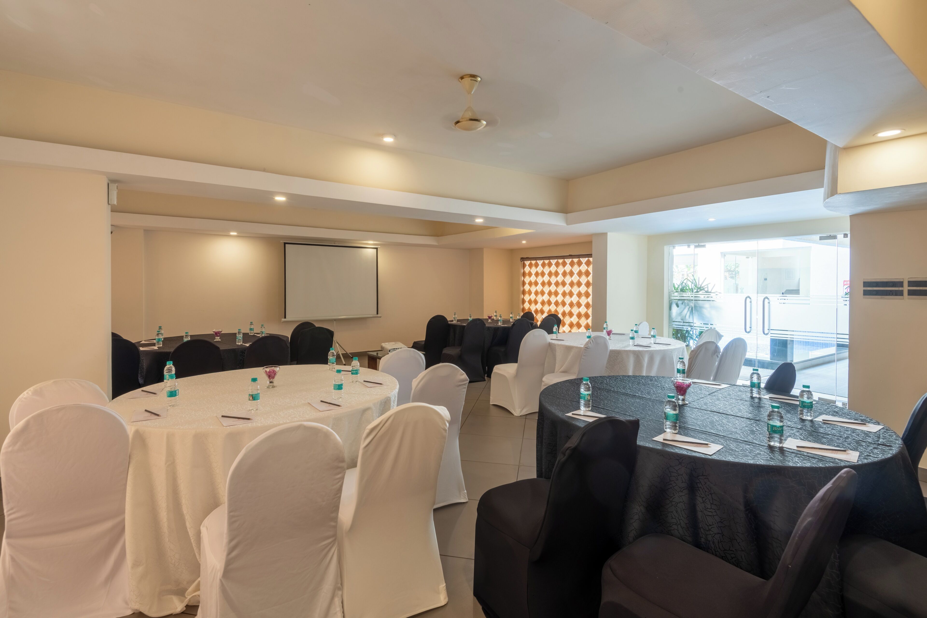 A conference room with round tables, white chairs, and water bottles.