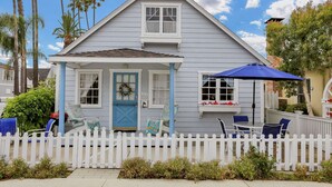 Ein Haus mit Veranda, einer blauen Tür und einem weißen Zaun.