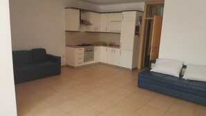 Een knus woongedeelte met een kitchenette, een bank en een eettafel.