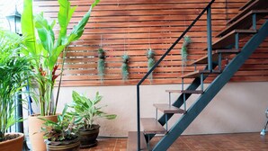 A staircase with a wooden finish and metal railings, surrounded by potted plants and terracotta tiles. - Private house in city center near Sukhumvit-Rama4 (Khwaeng Khlong Toei)