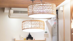 A compact kitchen with a wooden table set for dining, a microwave, and a shelf with decorative items. - Private house in city center near Sukhumvit-Rama4 (Khwaeng Khlong Toei)