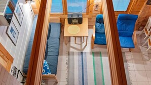 Ein kompakter, gut organisierter Wohnraum in einem Wohnmobil mit Bett, Sitzgruppe und kleinem Tisch mit Lautsprechern.