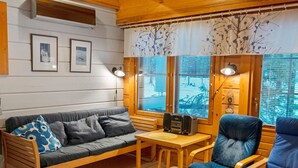 Ein gemütliches Zimmer mit Holzboden, einem grauen Sofa mit blauen Kissen, einem Holztisch mit einem Radio und einem blauen Sessel.