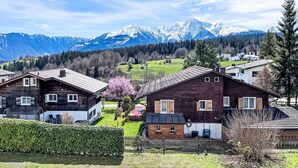 A rural village with wooden houses, a green field, and a mountain range in the background. - Girun Eder by Interhome (Flims)