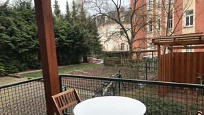 A balcony with a table and chairs, a metal fence, and a view of a garden and buildings in the background. - Guest apartment on Petersberg with balcony (Erfurt)