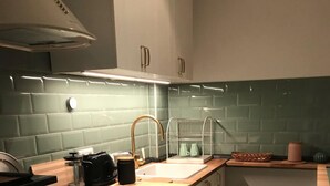 A compact kitchen with a gas stove, oven, and a sink with a modern faucet. - Guest apartment on Petersberg with balcony (Erfurt)