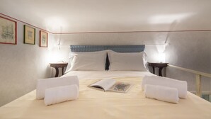 A hotel room with a bed, two bedside tables, a nightstand, and a wall with framed pictures. - An apartment in the heart of Santo Spirito by Mmega (Firenze)