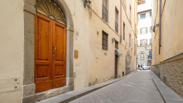 A narrow street with a large wooden door, stone walls, and a cobblestone path. - An apartment in the heart of Santo Spirito by Mmega (Firenze)